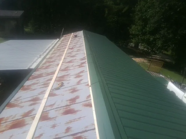 Old rusted panels beside newly installed green metal roofing — Wind Damage Roof Repair by Roofing Brothers in Hainesport