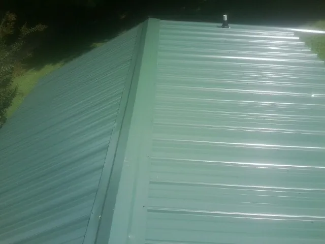 New green metal panels meeting at the ridge of a roof — Flat Roof Repair work by our crew in Hainesport
