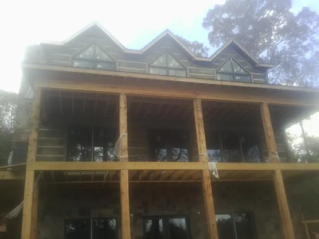 Dormers and porch framing on a large log home under construction — Roof Coating work by our crew in Hainesport