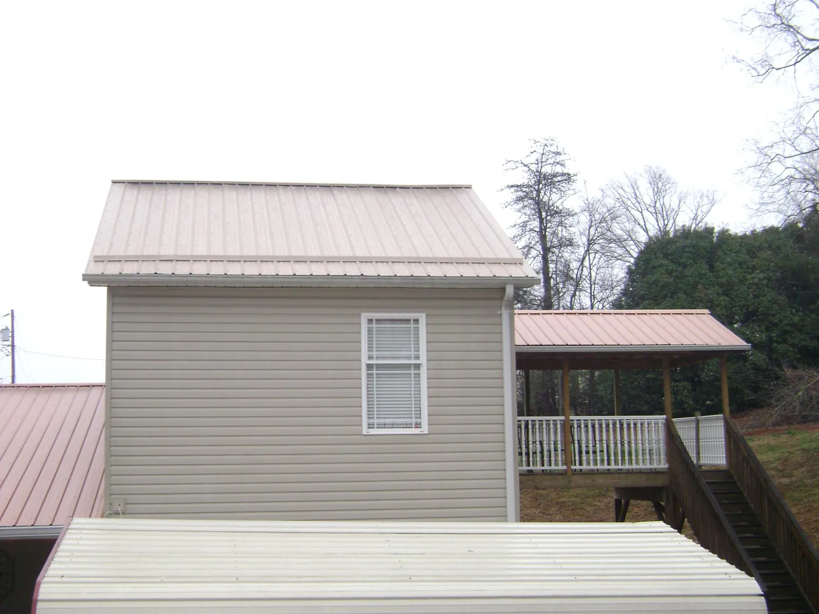 Tan metal roofs on a two story addition and attached porch, from a Roof Replacement job in Hainesport