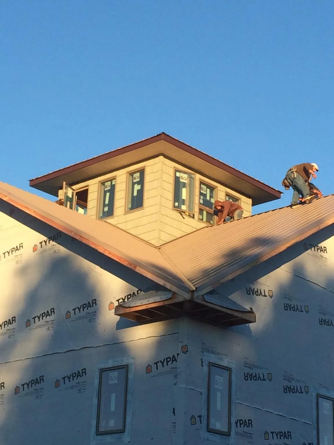 Roofers working around a rooftop cupola on a new metal roof at sunset — Roof Waterproofing in Hainesport by Roofing Brothers